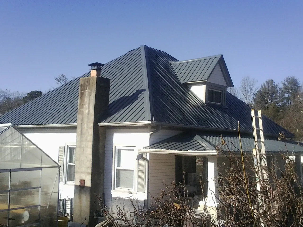 Dark blue standing seam metal roof on a white farmhouse with dormer — Slate & Tile Roof Repair by Roofing Brothers in Stirling City