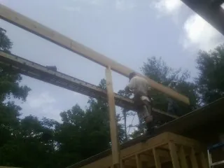 Carpenter setting a ridge beam over a new addition frame — Ice Dam Removal by Roofing Brothers in Stirling City