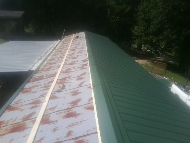 Old rusted panels beside newly installed green metal roofing — Wind Damage Roof Repair by Roofing Brothers in Stirling City