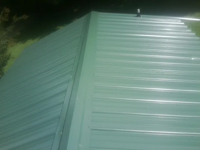 New green metal panels meeting at the ridge of a roof — Flat Roof Repair work by our crew in Stirling City