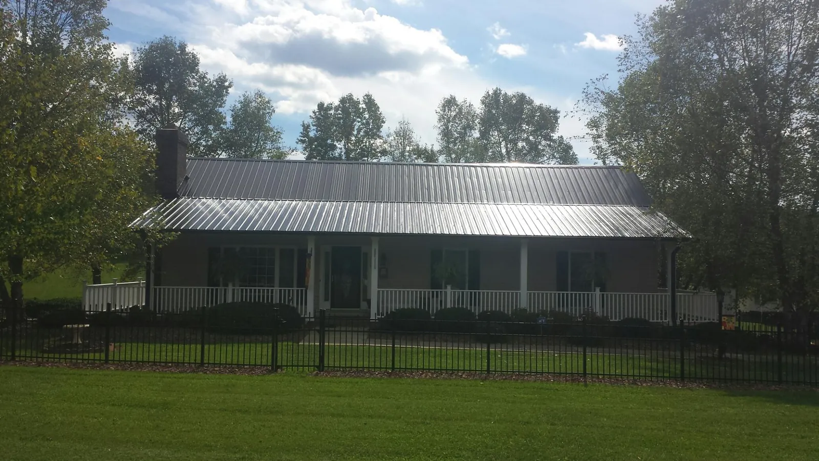 Gray metal roof on a brick ranch with a full width front porch — Gutter Guard Installation work by our crew in Stirling City