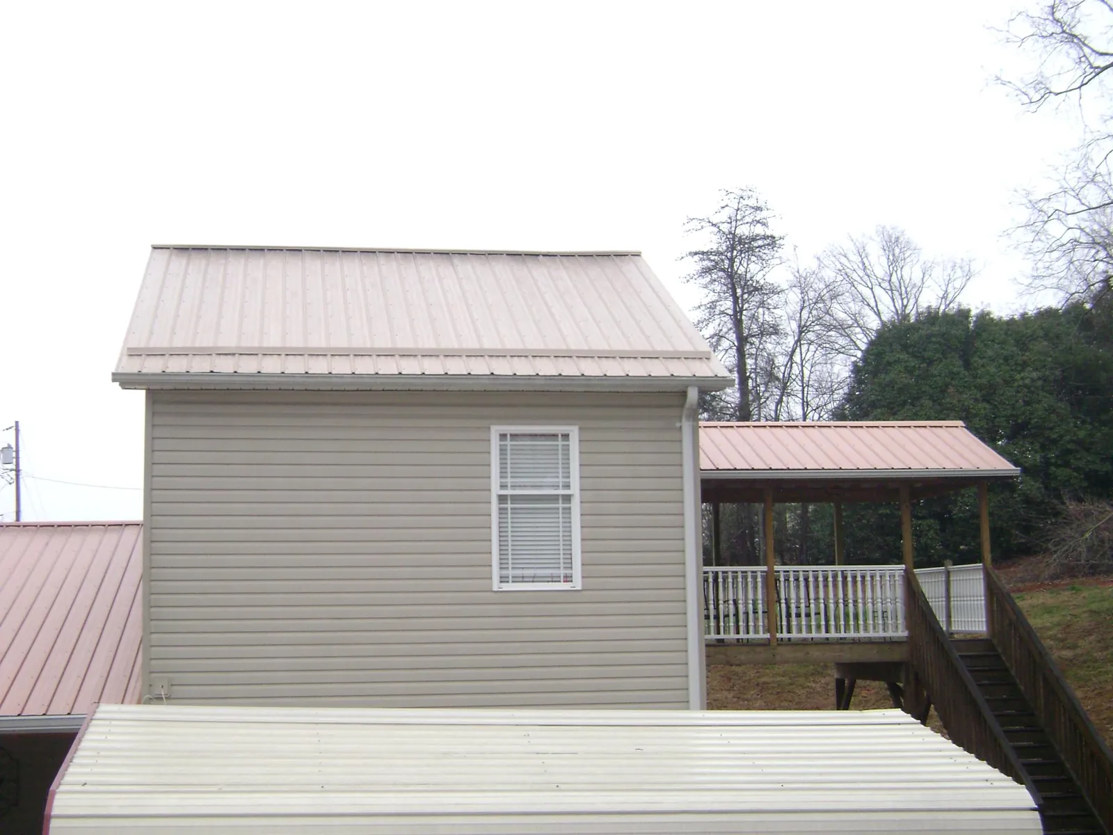 Tan metal roofs on a two story addition and attached porch, from a Roof Replacement job in Stirling City
