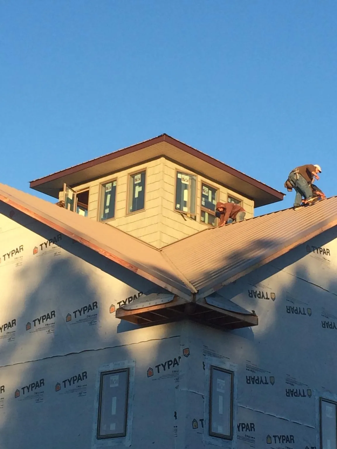 Roofers working around a rooftop cupola on a new metal roof at sunset — Roof Waterproofing in Stirling City by Roofing Brothers